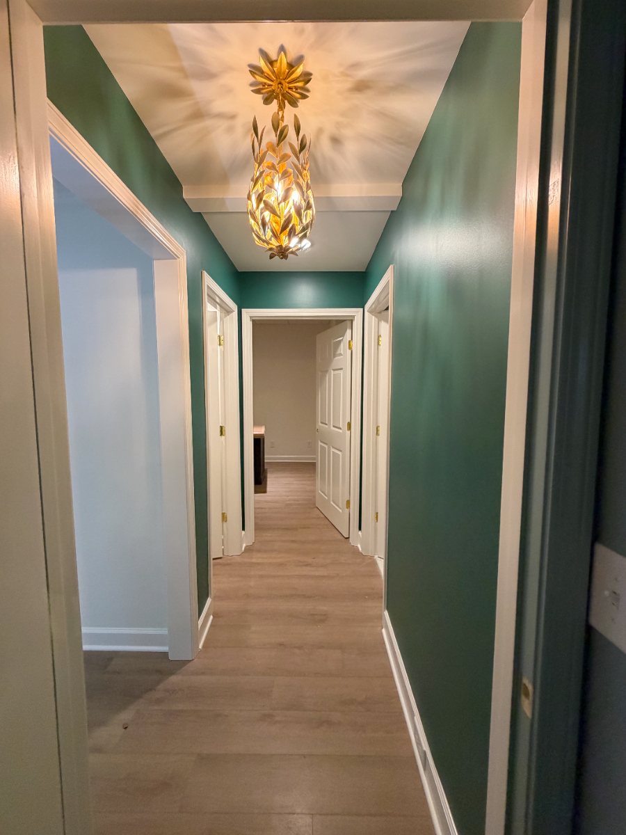 Hallway painted deep green with white trim and a bright ceiling
